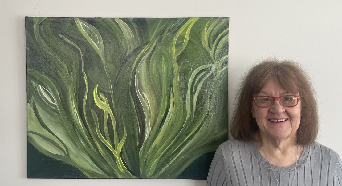 Diane Reiter poses with a painting she made in her home in the suburbs of Chicago.