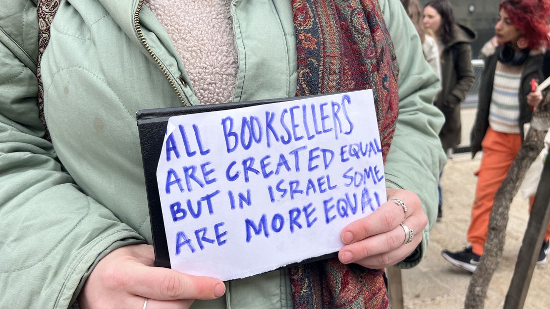 A protester holding a sign in front of a courthouse after the Educational Bookshop was raided in February.