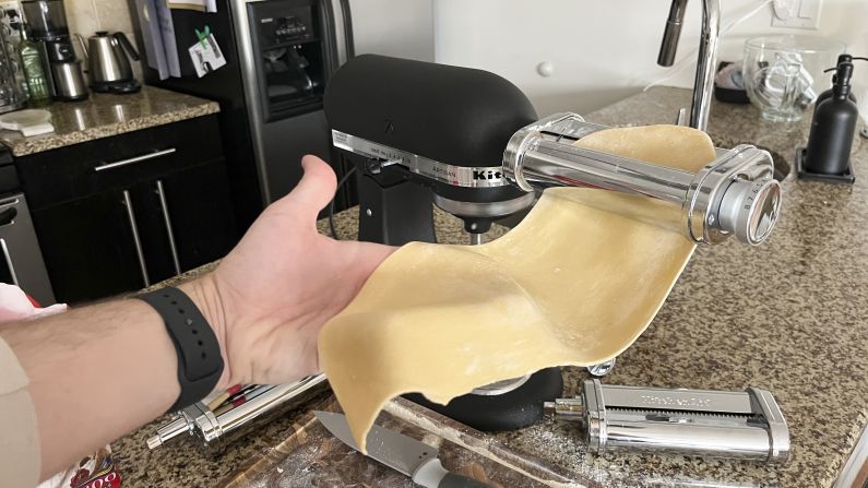 A sheet of pasta is flattened in the KitchenAid pasta roller.