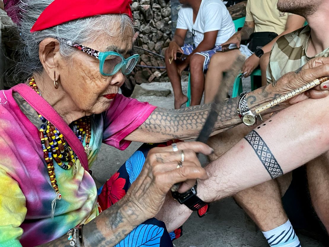 Whang-Od hammers away on a visitor's arm.