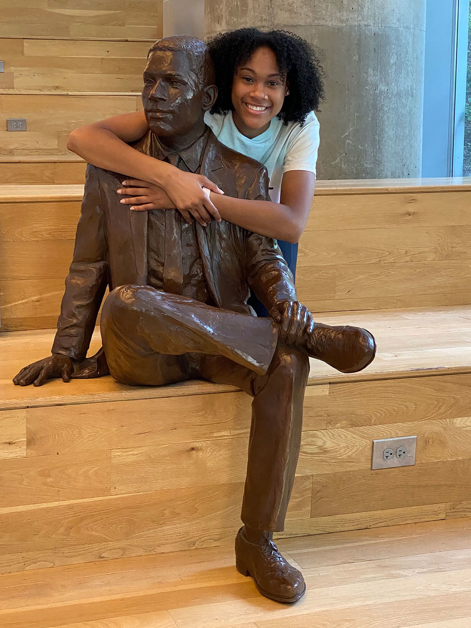Deanna Yancey smiles with a statue of her grandfather, Ronald, who was the first Black student to graduate from Georgia Tech in 1965.