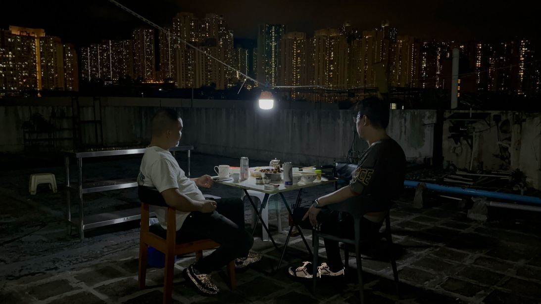 Residents of a rooftop structure atop an industrial building in Kwun Tong, Hong Kong eat dinner on July 8, 2025.