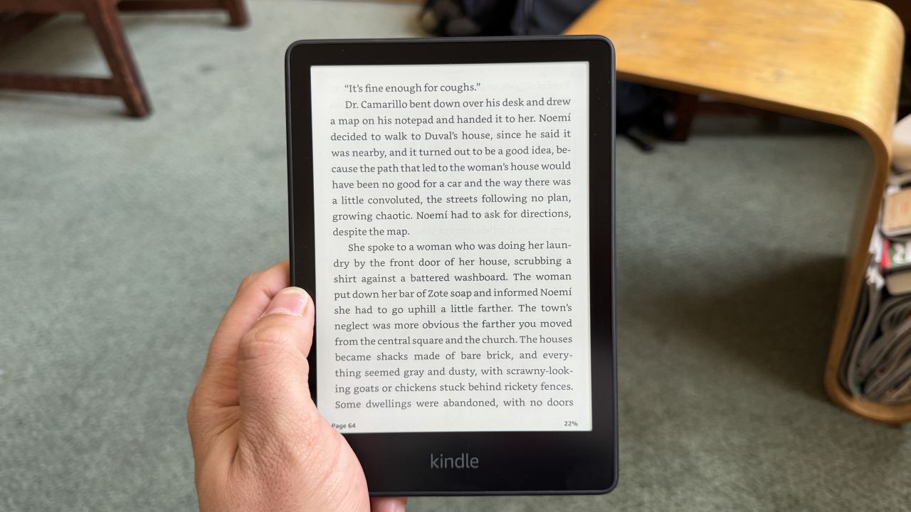 A Kindle Paperwhite is held in a hand, and it's open to a page of text.