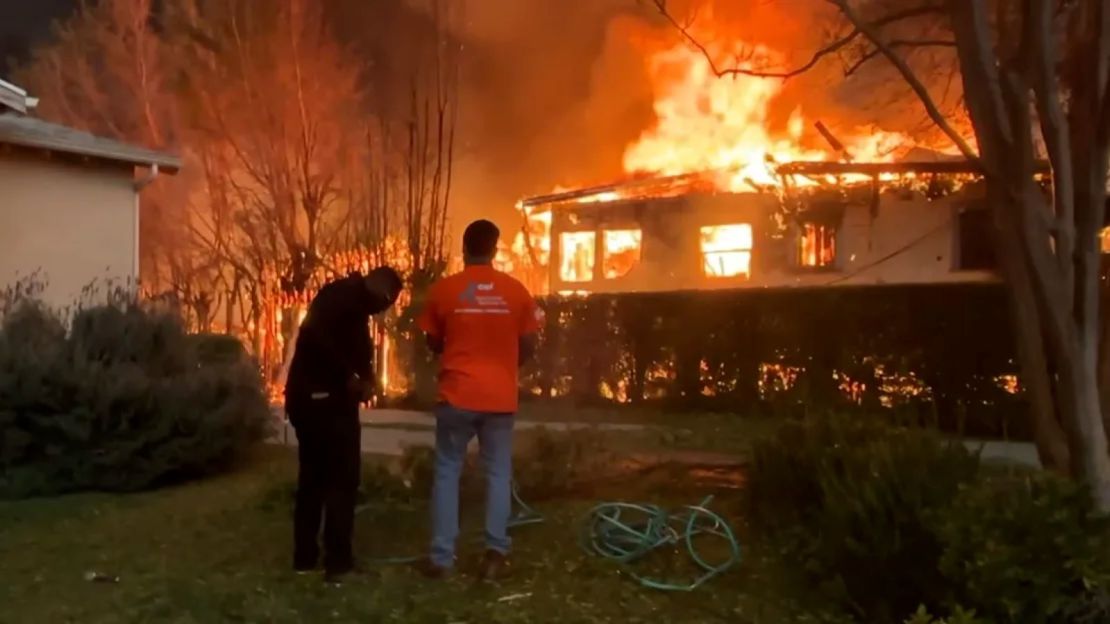 Voluntarios intentan apagar el fuego en la casa y el jardín de Gail para mantener las llamas a raya.