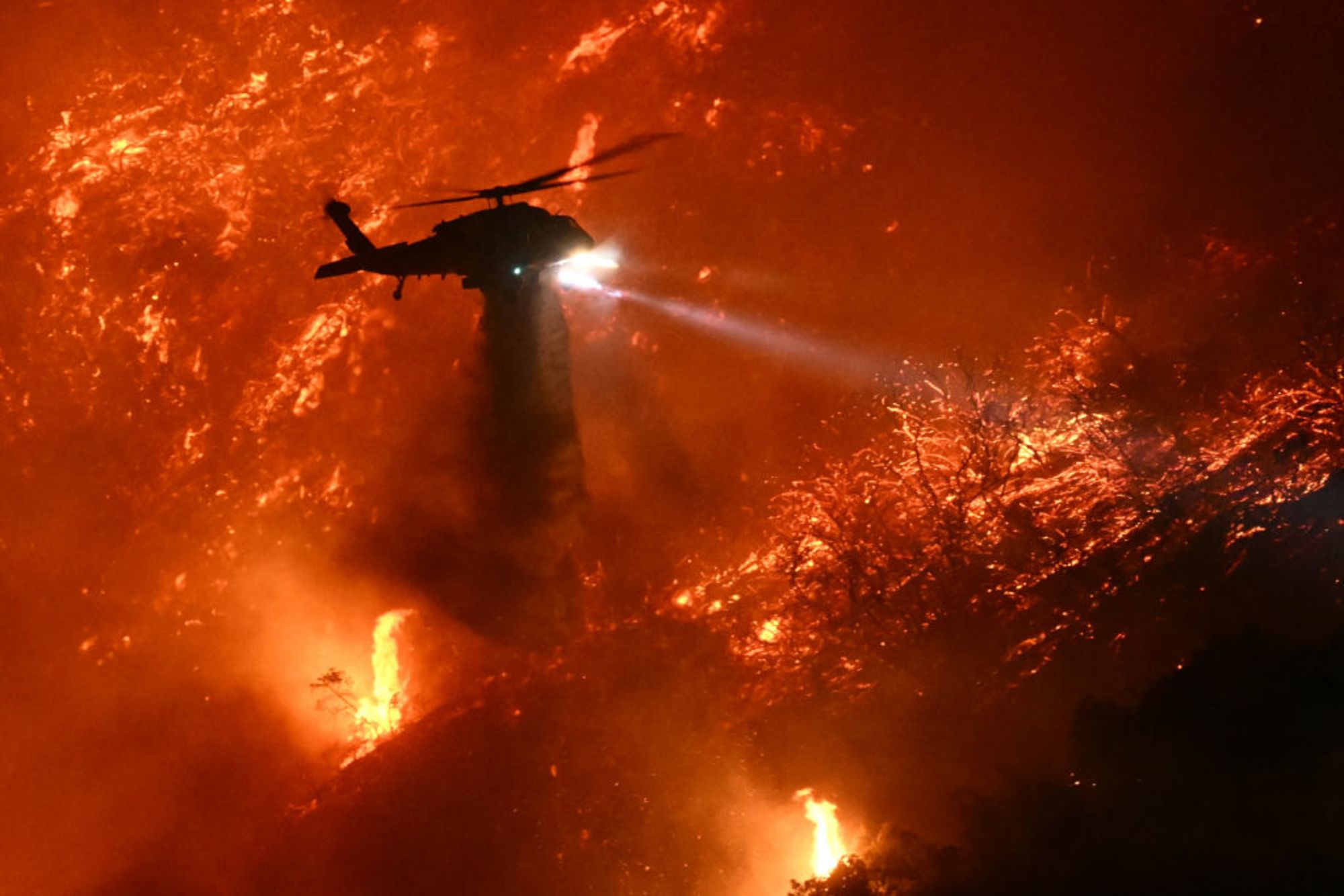 Un helicóptero de extinción arroja agua mientras el incendio Palisades crece cerca del vecindario de Mandeville Canyon y Encino, California, el 11 de enero de 2025.