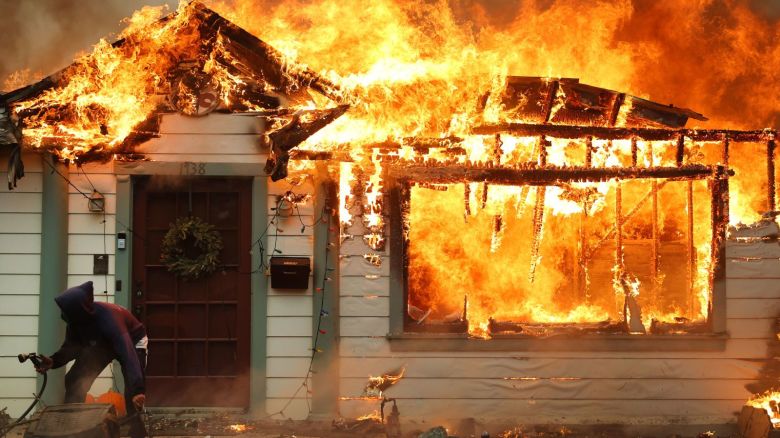 Un residente usa una manguera de jardín para intentar salvar una casa vecina en Altadena, California. Mario Tama/Getty Images