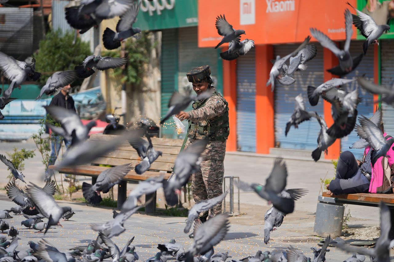 Un soldado indio alimenta palomas en un mercado de Srinagar, en Cachemira istrada por la India, el domingo.