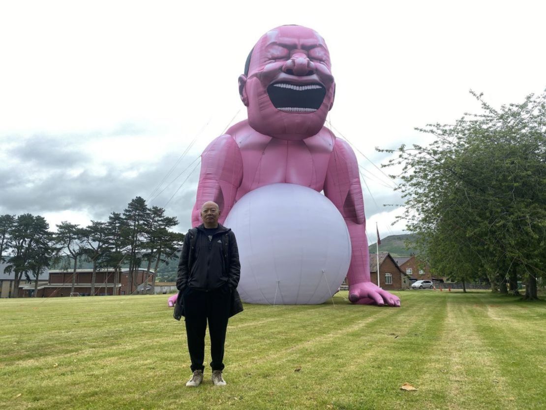 Yue Minjun frente a su instalación de arte inflable.