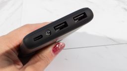 A photo of a hand holding an INIU power bank over a table