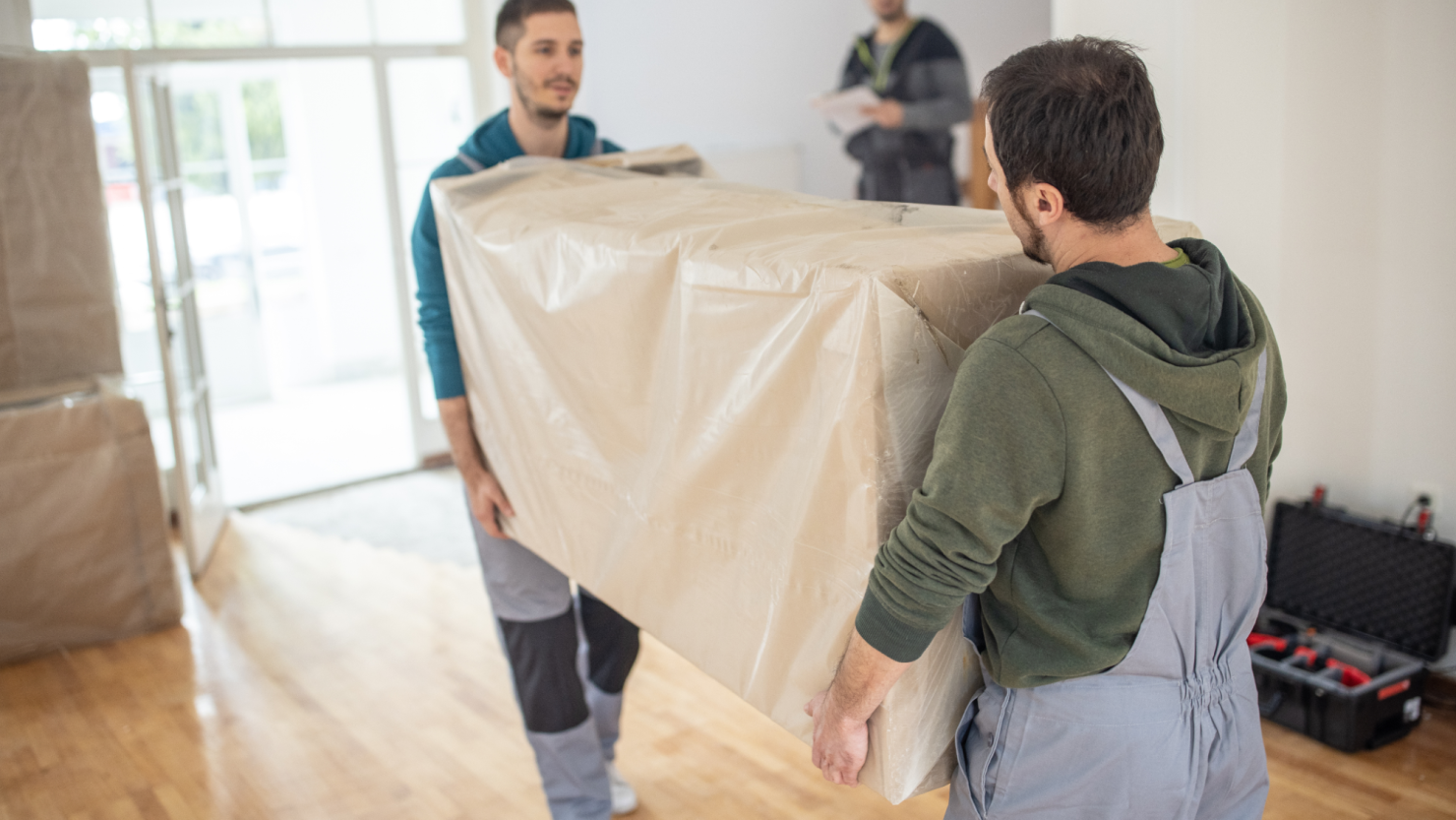 Professional movers carrying in new furniture in a cardboard box
