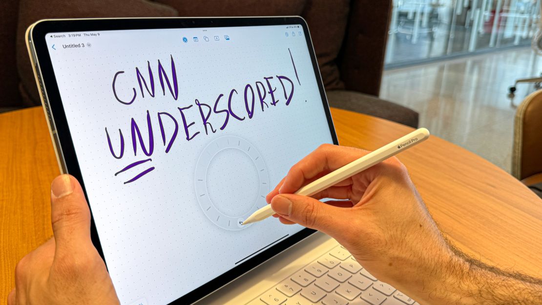 A hand writes "CNN Underscored!" on an iPad Air with the Apple Pencil Pro