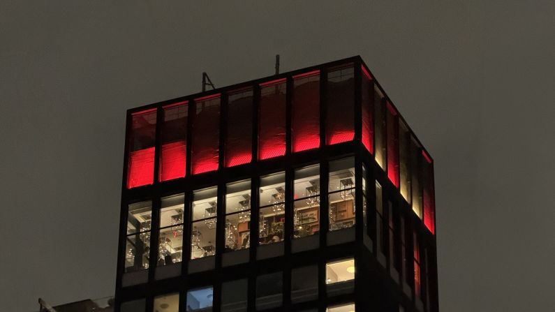 The view of a skyscraper at night from ground level.