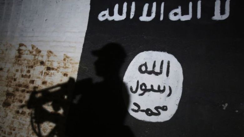 Un miembro de las fuerzas iraquíes pasa junto a un mural con el logotipo del ISIS en un túnel que, según informes, fue utilizado como centro de entrenamiento por los yihadistas, el 1 de marzo de 2017, en la aldea de Albu Sayf, en las afueras del sur de Mosul.