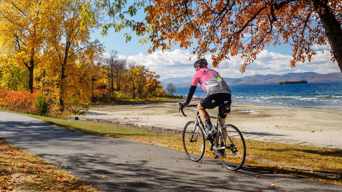 Load up the bicycles for your Lake Champlain Byway drive in Vermont. This biker rides the Island Line in Burlington with a enviable view of Lake Champlain and beyond, the Adirondack Mountains of New York.