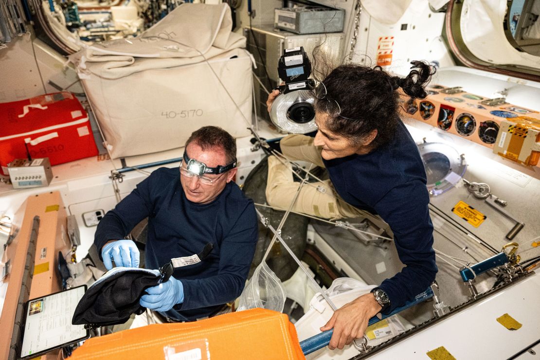 Astronot Butch Wilmore (kiri) dan Sonny Williams – masing-masing komandan uji penerbangan awak Boeing dan pilot – memeriksa perangkat keselamatan di Stasiun Luar Angkasa Internasional pada 9 Agustus.