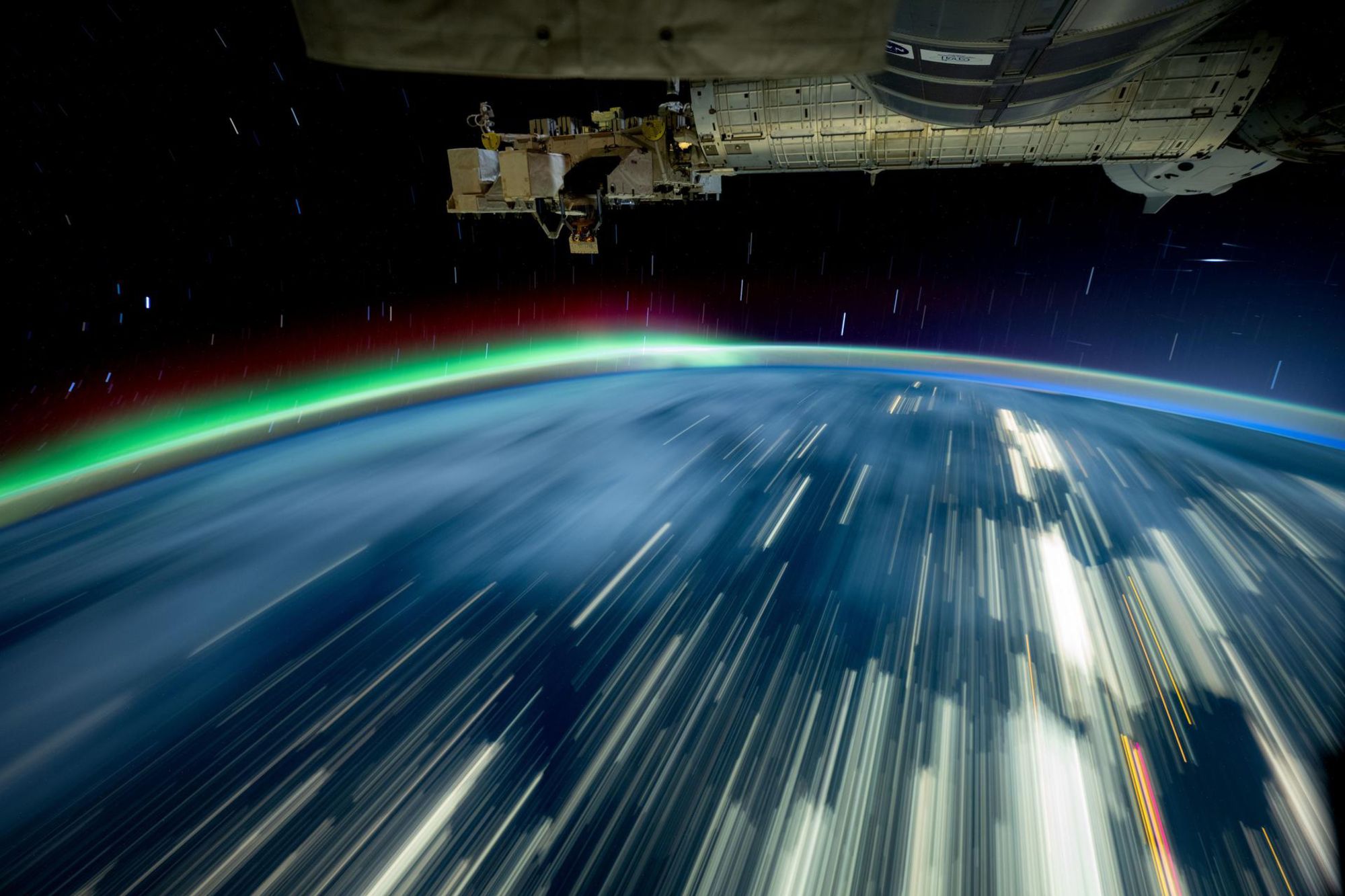 As the International Space Station soars 257 miles above Lake Michigan in October, NASA's Don Pettit captures a long-exposure photo of city lights across Earth and a red-and-green aurora.