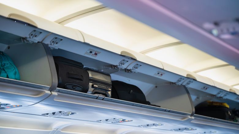 A photo of suitcases in the overhead compartment of a commercial airplane