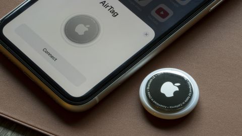 A photo of an Apple AirTag next to an iPhone