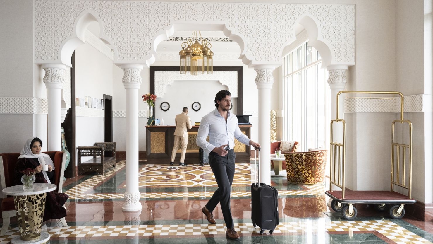 A photo of a person walking through a luxurious hotel lobby with a suitcase