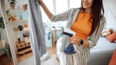 A photo of a person steaming a shirt with a handheld clothes steamer