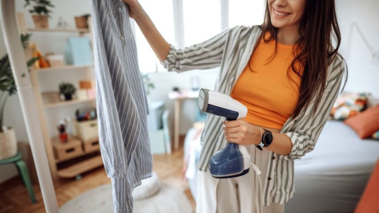 A photo of a person steaming a shirt with a handheld clothes steamer