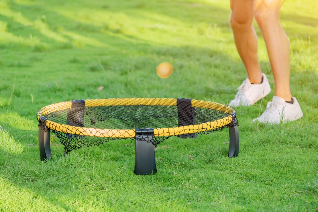 Playing ball with mini beach volleyball net on a green grass lawn. Modern Leisure sports and fun recreation with friends