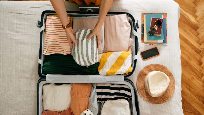 A photo of a person packing a suitcase on top of a bed