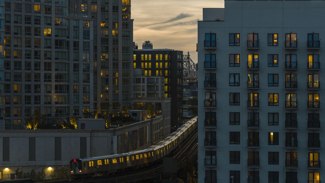 A photo of a Subway train riding through two apartment buildings in Long Island City, Queens in New York City