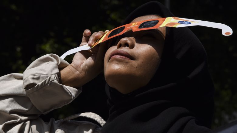 A photo of a person looking at a solar eclipse through eclipse glasses in Bandung, West Java, Indonesia