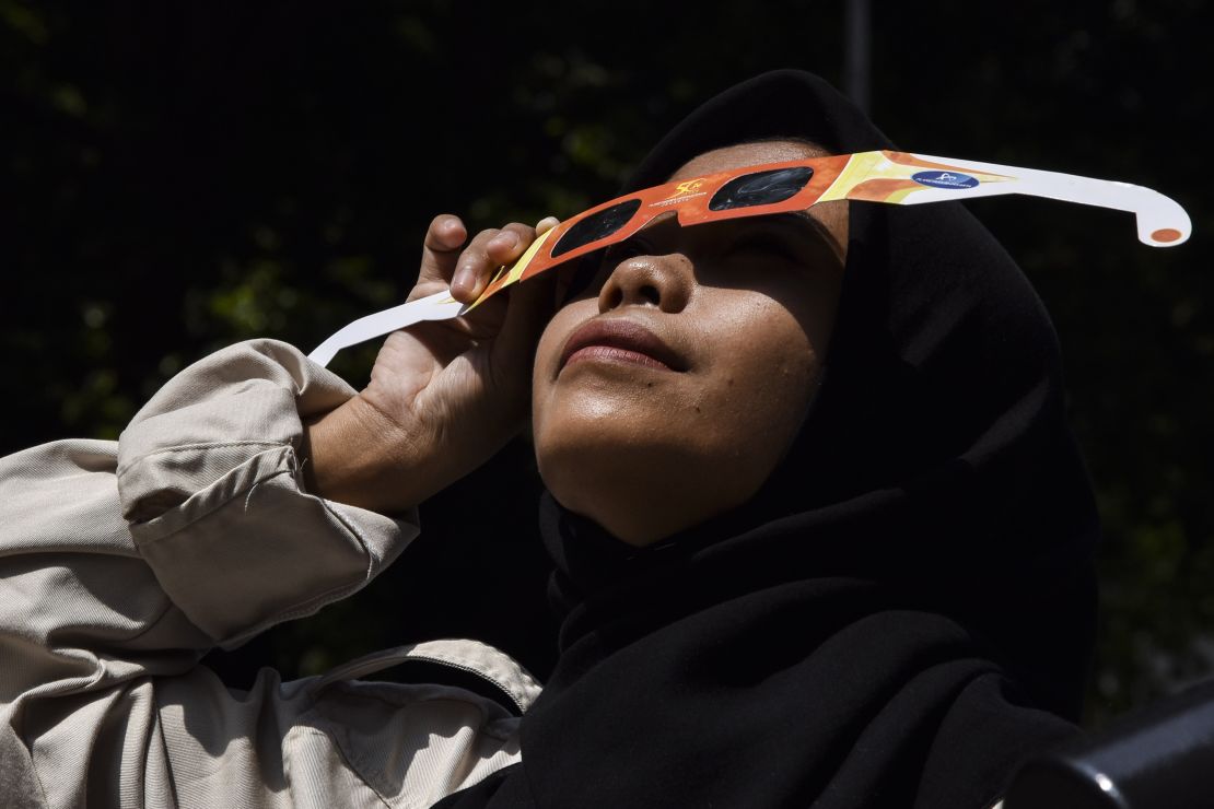 A photo of a person looking at a solar eclipse through eclipse glasses in Bandung, West Java, Indonesia