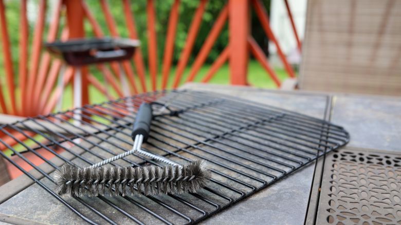 A close up of a charcoal grill scrubbing brush sitting on a dirty rack