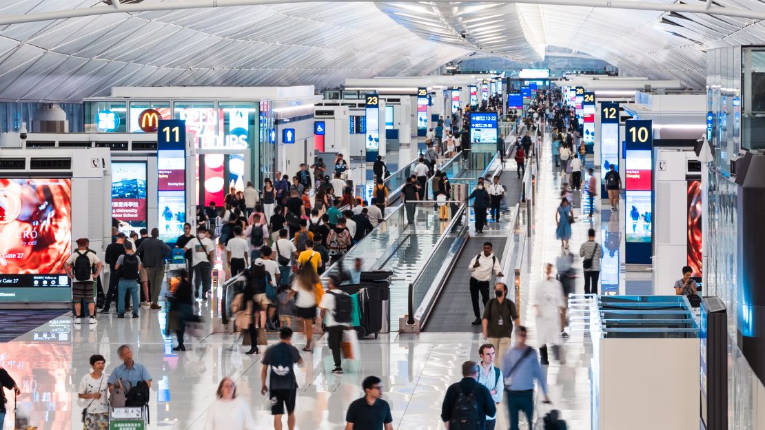 A photo of travelers walking through a busy airport terminal in Hong Kong