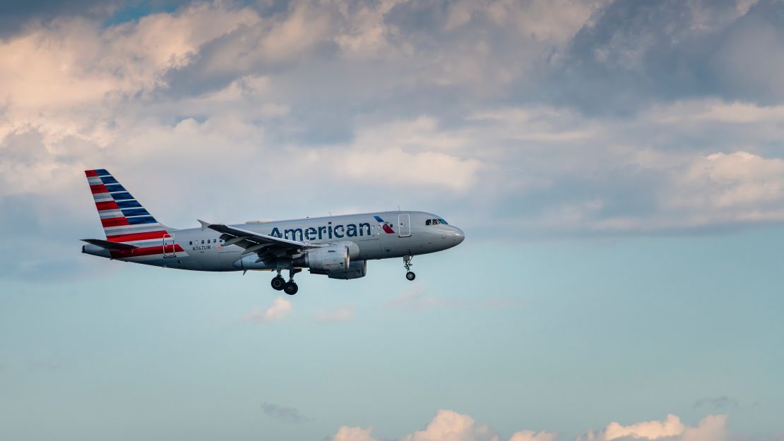 A photo of an American Airlines jet flying near Toronto with a blue sky and clouds in the background