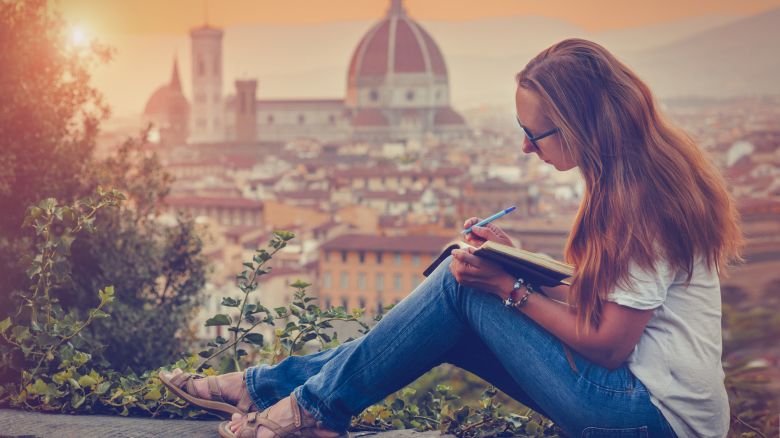 A photo of a person writing notes in Florence, Italy with historic buildings in the background