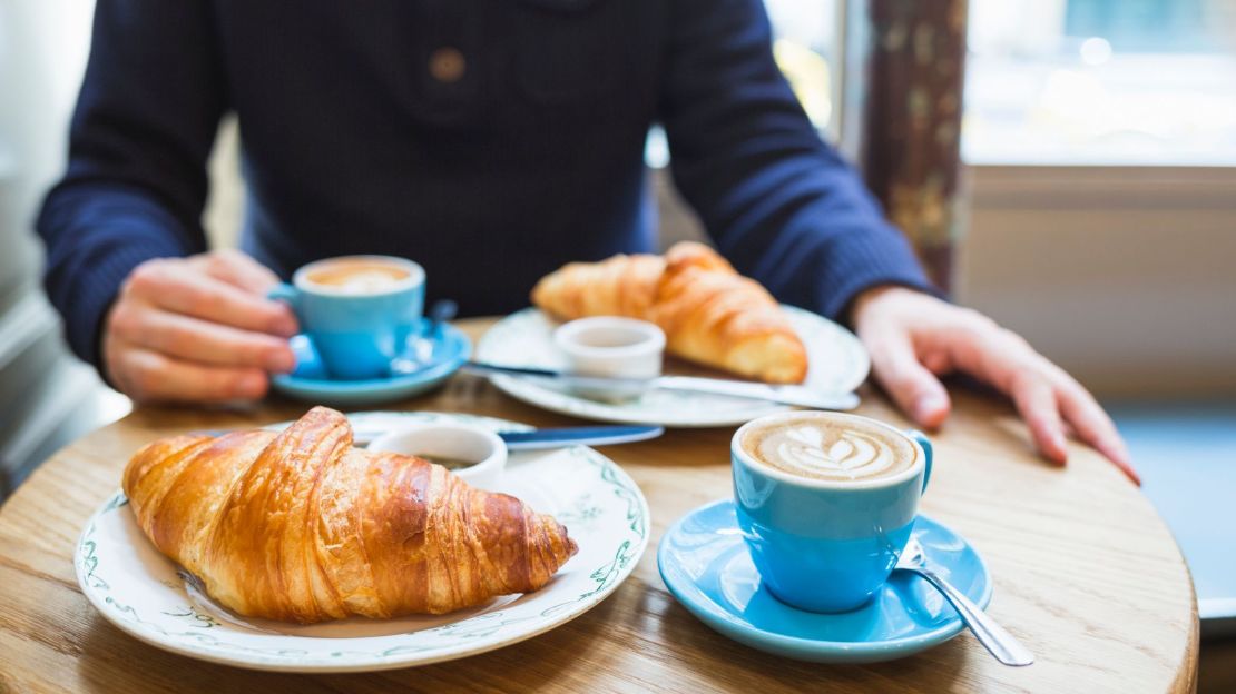 A photo of two cappuccinos and two croissants on a table at a cafe in Paris, France