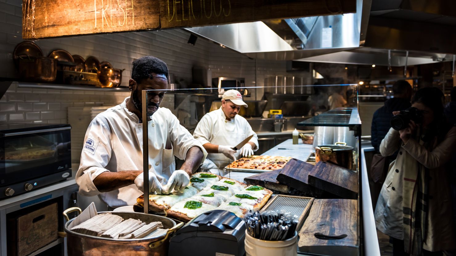 A photo of two people preparing food in a kitchen inside of New York City's Chelsea Market