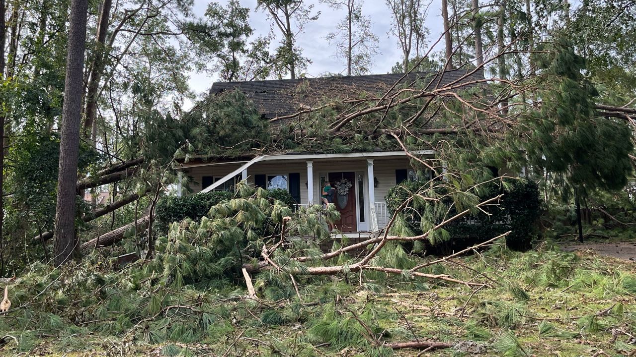 Kristin Jones holds her son tight on the porch of their house after the roof was crushed by falling trees during Hurricane Helene.