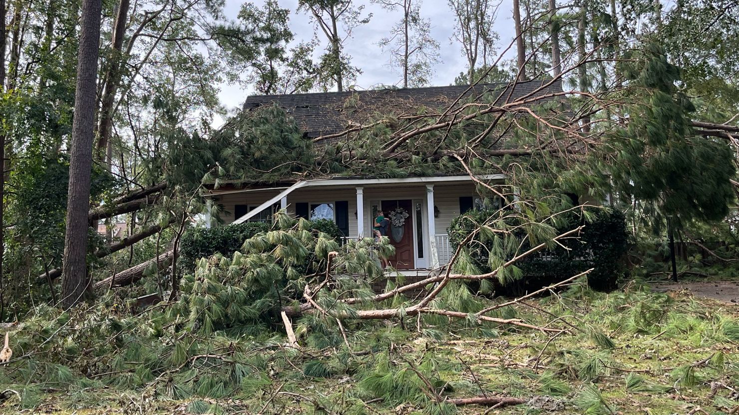 Kristin Jones holds her son tightly on the porch of their house after the roof was crushed by falling trees during Hurricane Helene.