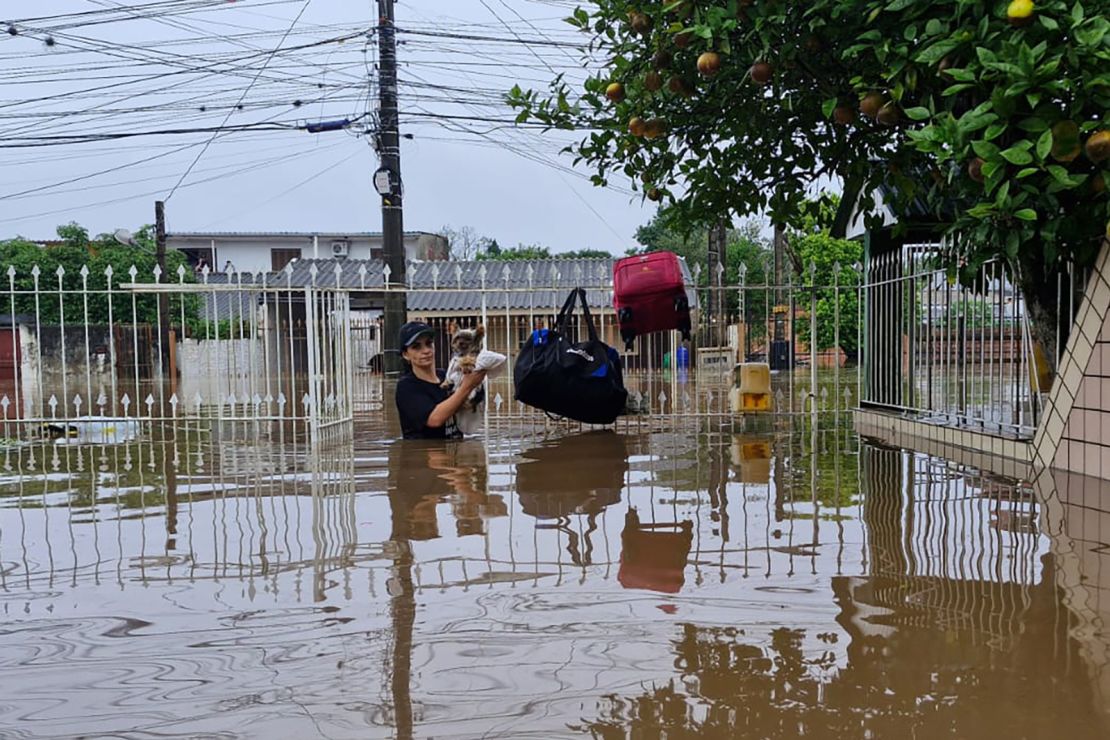 Karine Pitana, 42, holding her small dog, when she left her home. Two weeks later, parts of her home remain underwater and she’s still not able to go back.