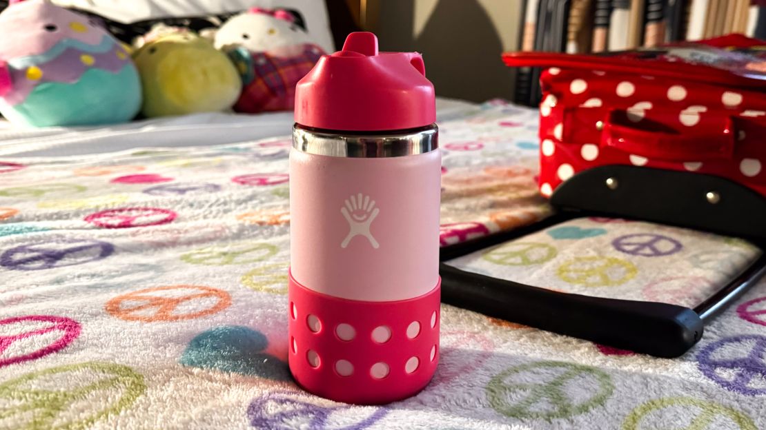 A photo of a pink Hydro Flask 12-Ounce Kids Wide Mouth Water Bottle on a bed