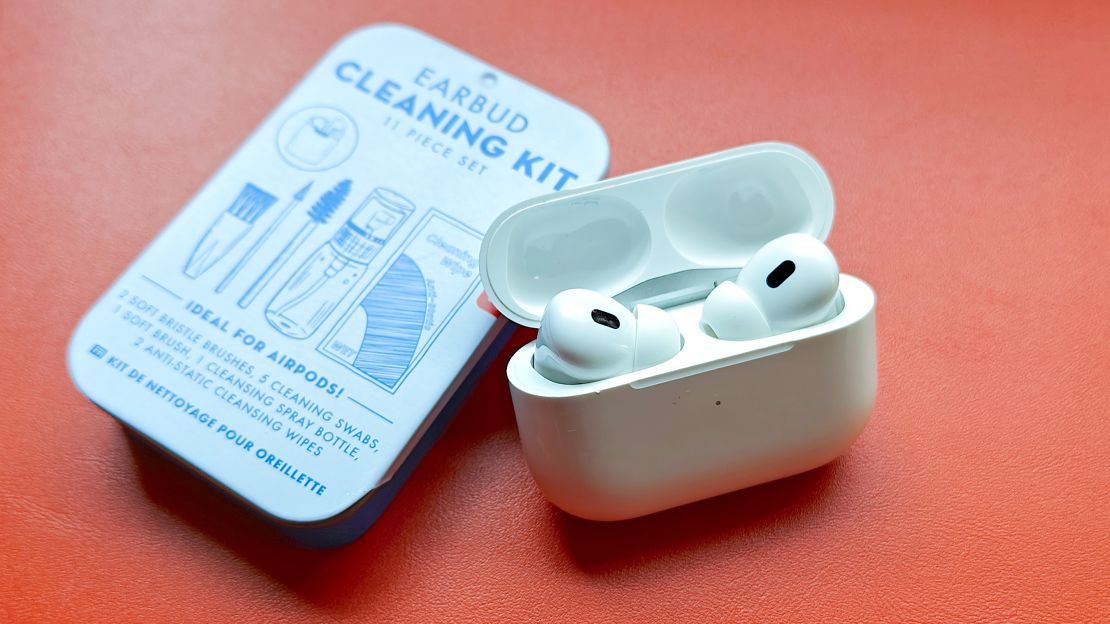 An open AirPods Pro case leans on the tin of the Kikkerland Earbud Cleaning Kit.