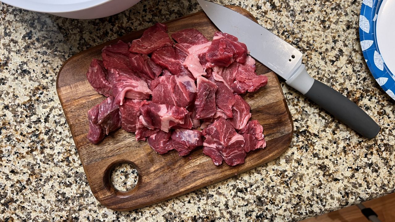 A pile of raw beef on a wooden cutting board.