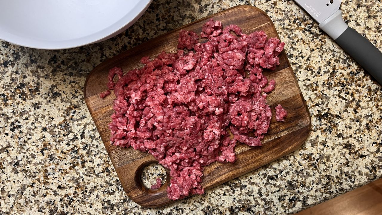 A pile of ground beef on a wooden cutting board.