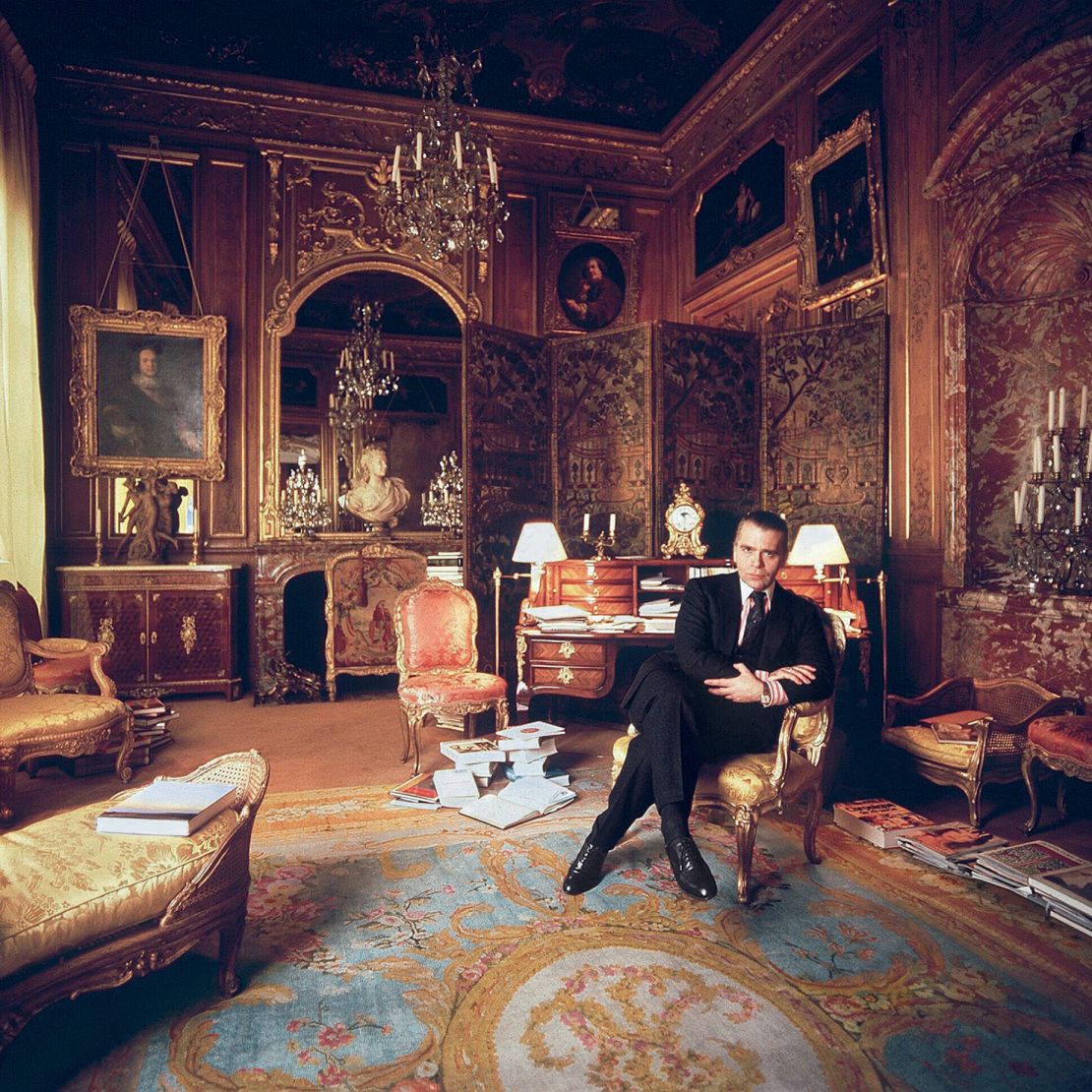 Lagerfeld in his residence in the Hôtel Pozzo di Borgo circa 1990. Across some three decades of his life, Lagerfeld lived in different parts of the building; in outfitting his homes therein, he "returned to the dreams of grandeur and elegance that had been sparked in him as a child," Kalt wrote of Lagerfeld and the <em>ancien regime</em>-worthy aesthetic on display.