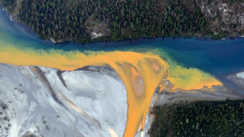 An aerial view of the Kutuk River in Alaska's Gates of the Arctic National Park that looks like<br />orange paint spilling into the clear blue water.