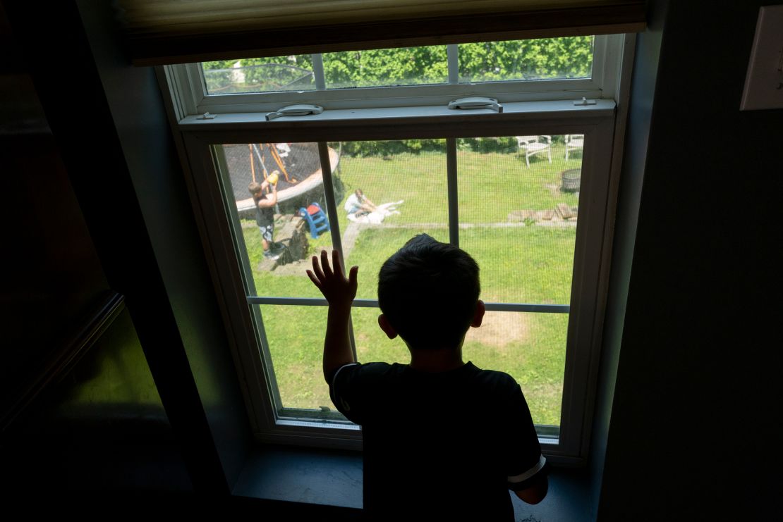 Junior watches through a window as friends and family play outside during a going-away party.
