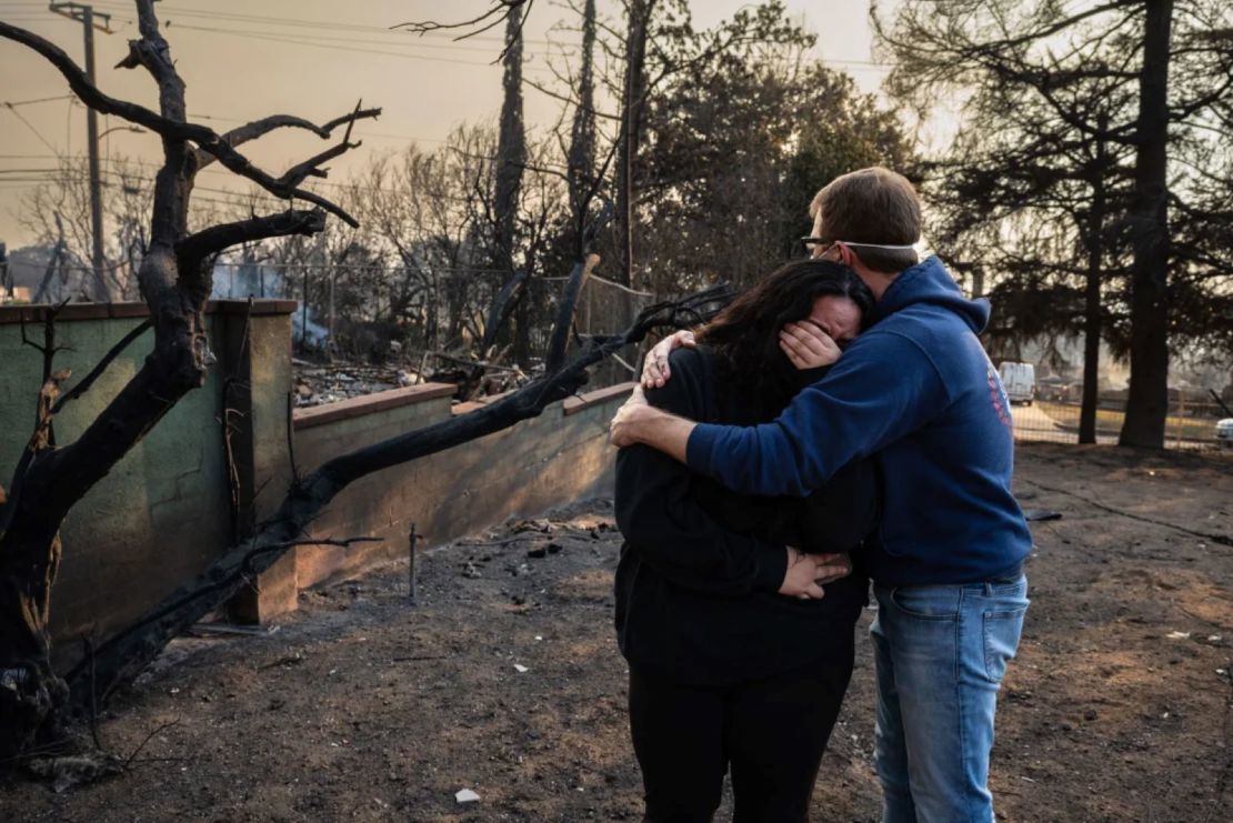 Un hombre consuela a su hija junto a las ruinas carbonizadas de su hogar familiar, que se quemó en el incendio de Eaton en Altadena, California.