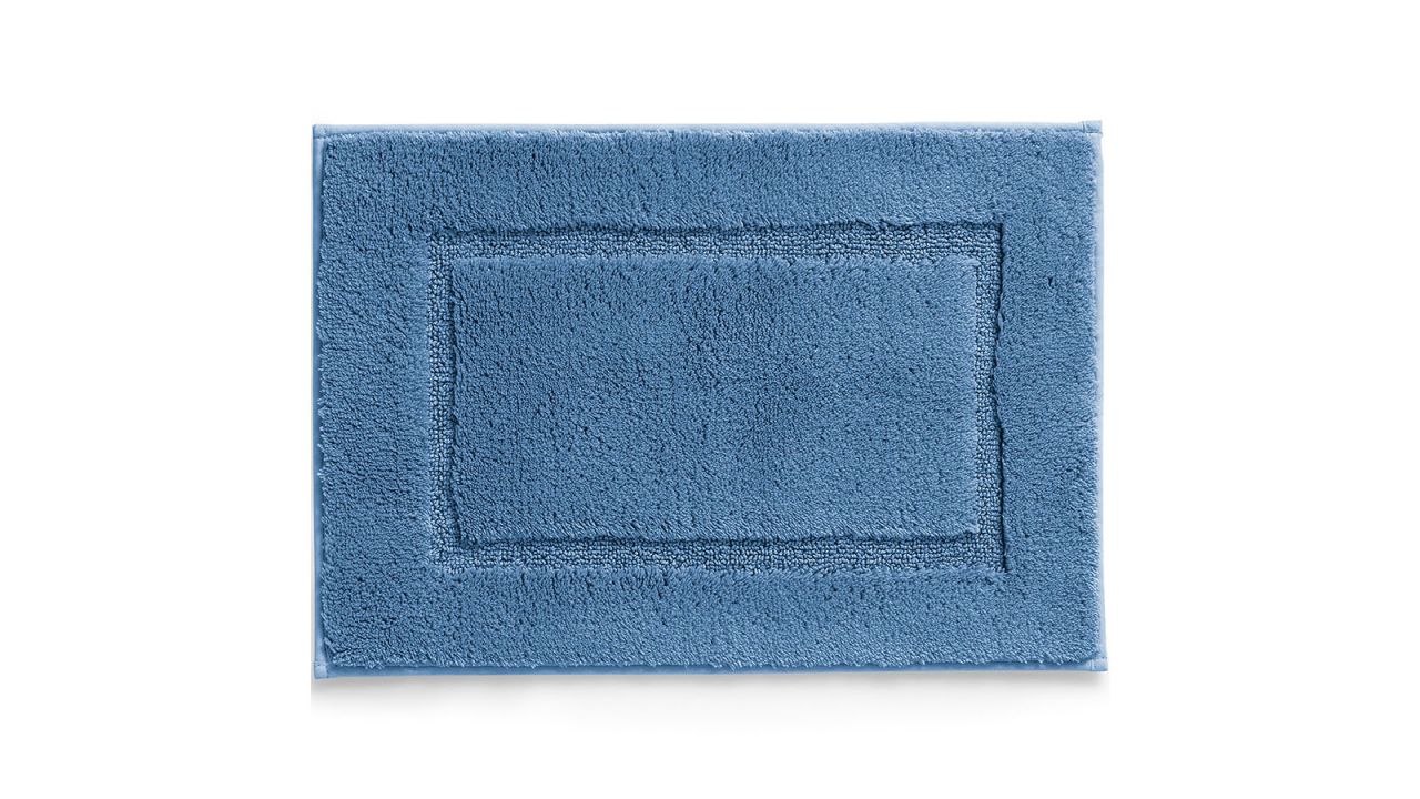 Blue bath rug placed against white background.
