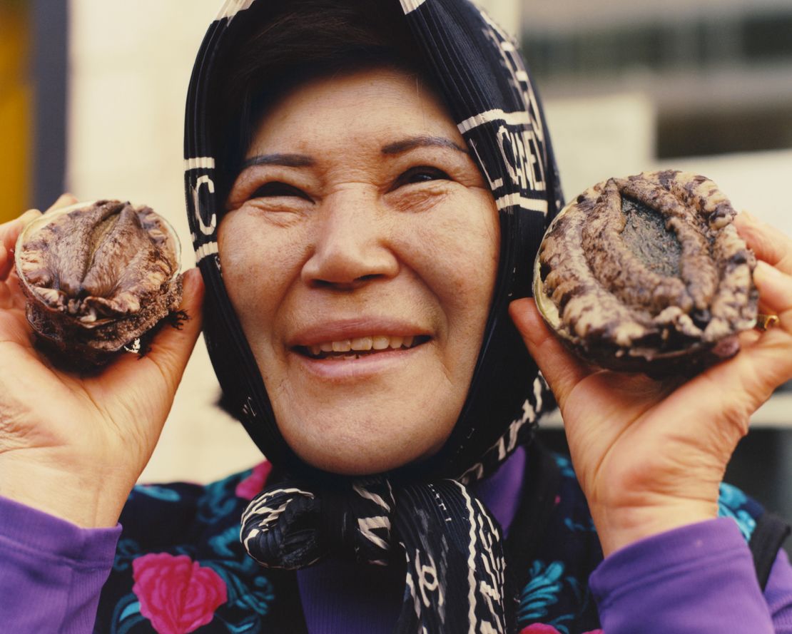 A woman holds fresh abalone, a historic delicacy in Korea.