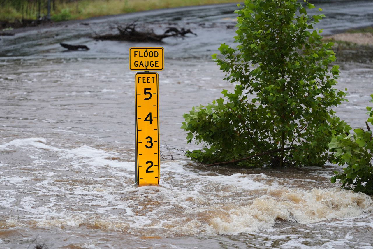 Un indicador de inundaciones marca la altura del agua que fluye sobre una carretera cerca de Kerrville, Texas, el viernes.